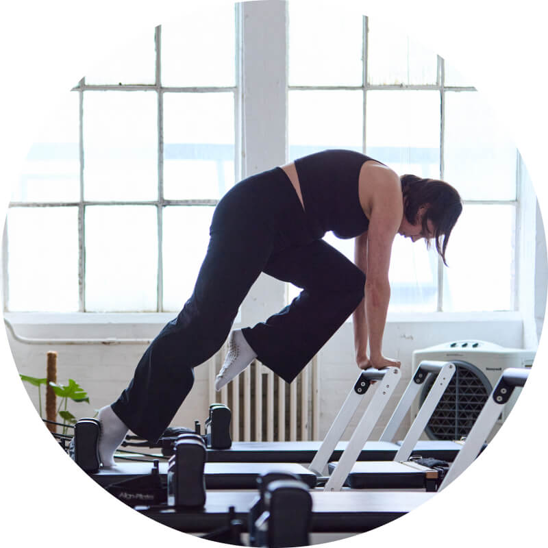 Martha practicing reformer pilates in from of the sunny windows of the bussey building in Peckham