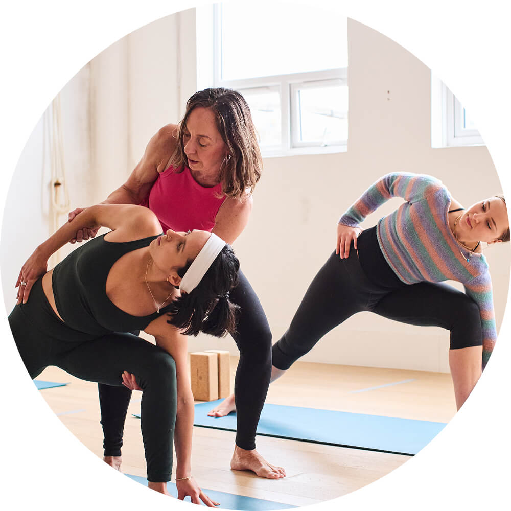 Leela Miller adjusts a student in an Ashtanga yoga class in Yogarise Queen's Park